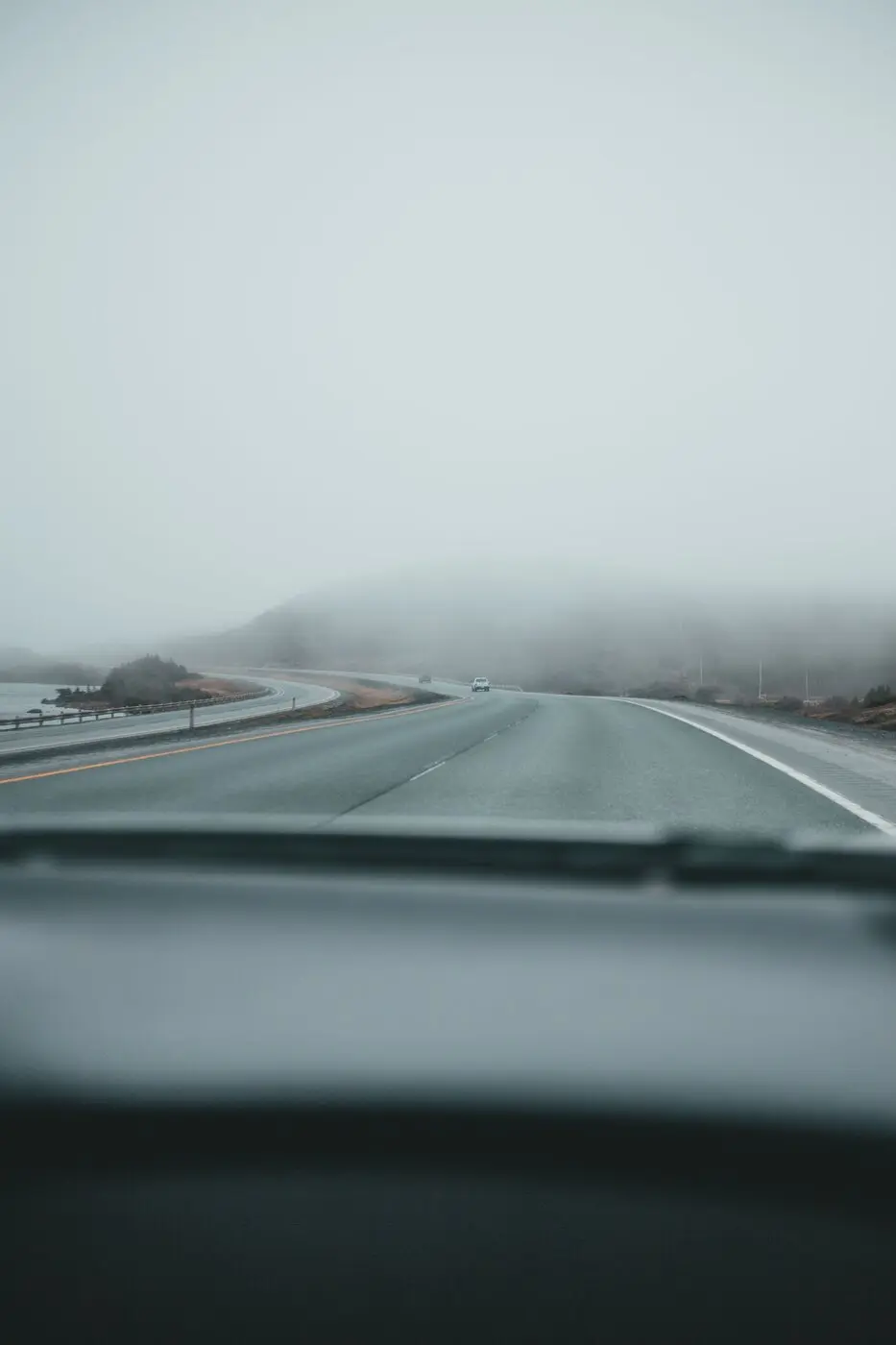 Vista desde adentro de un auto manejando en una ruta con niebla